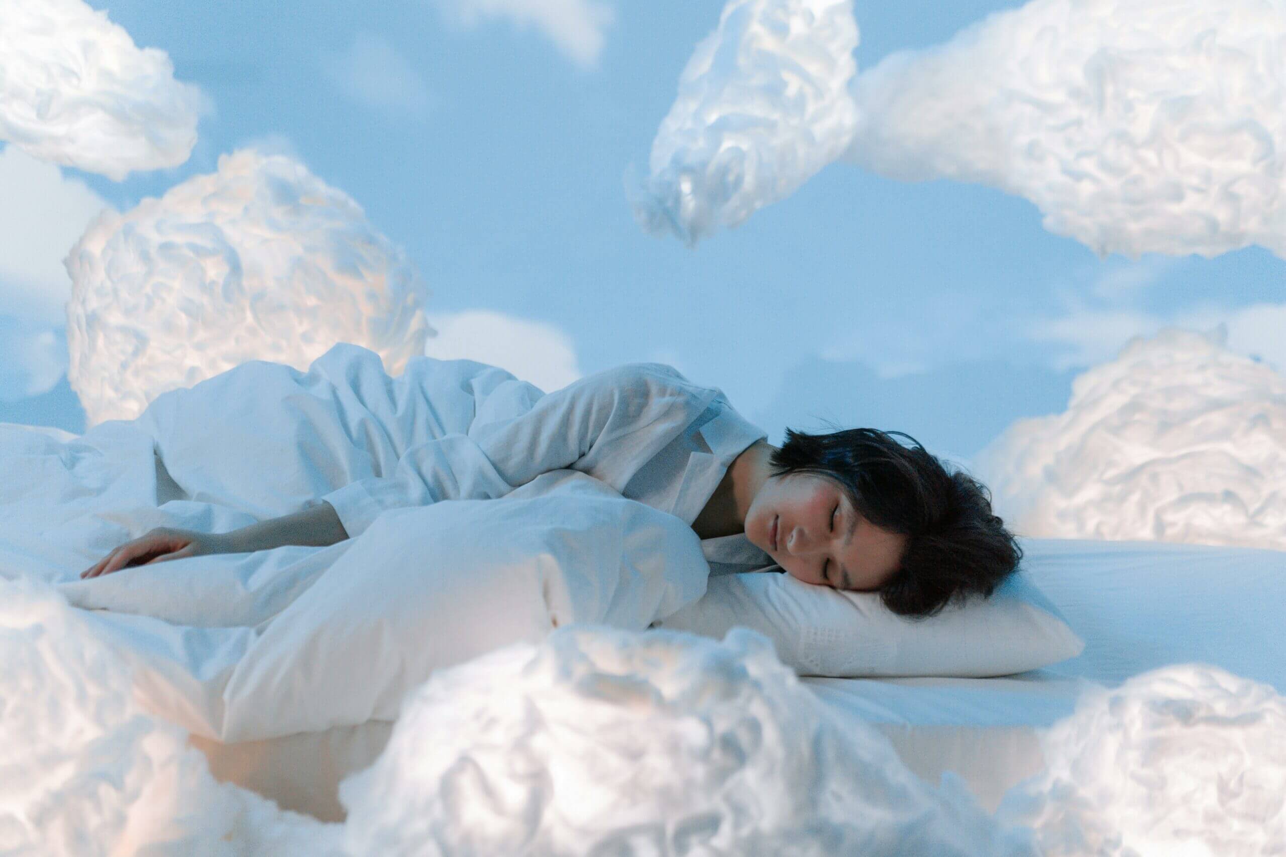 femme sur un matelas dans les nuages et ciel bleu